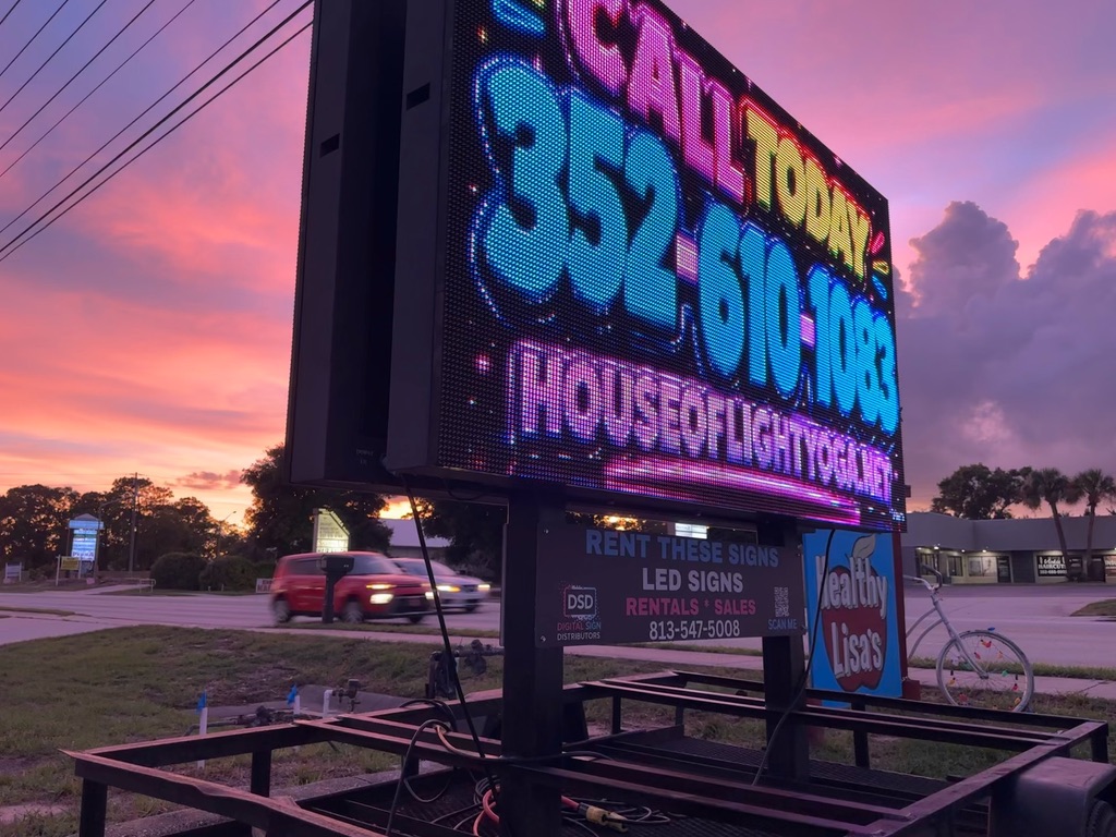 Parked LED sign trailer glowing at sunset on a Florida roadside, reading Call Today